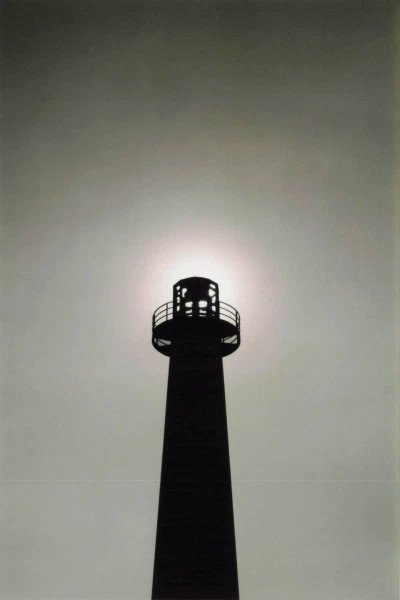 A lighthouse silhouetted against a bright night sky