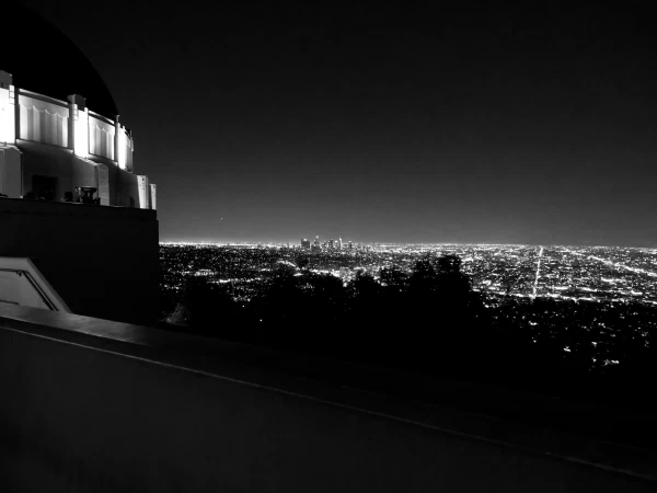 City lights spread below a hillside overlook, in black and white